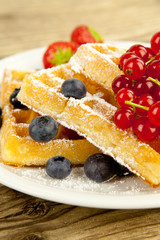 Frische Waffeln mit Puderzucker und Beeren auf einem Tisch