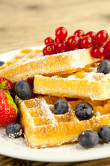 Frische Waffeln mit Puderzucker und Beeren auf einem Tisch