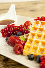 Frische Waffeln mit Puderzucker und Beeren auf einem Tisch
