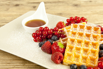 Frische Waffeln mit Puderzucker und Beeren auf einem Tisch