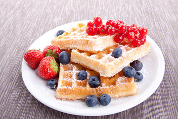 Frische süße Waffeln mit Puderzucker und beeren auf einem Tell