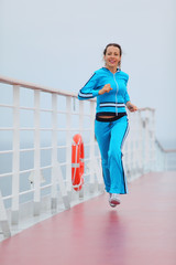 Fototapeta na wymiar Beautiful woman wearing in blue sports suit runs on cruise liner