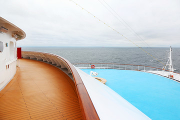Snout with railing of large cruise ship. View from wooden deck.