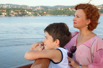 Fototapeta na wymiar Mother and son are on board of ship and look at landscape