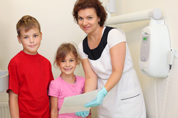 Obraz premium Dentist shows jaw x-ray image for girl and boy in dental clinic