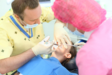 Obraz premium Dentist makes injection to girl sitting in chair