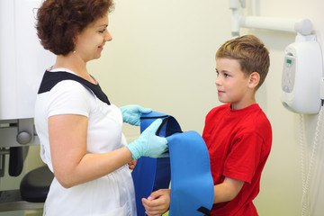 Dentist wears protective lead apron to boy for jaw x-ray image