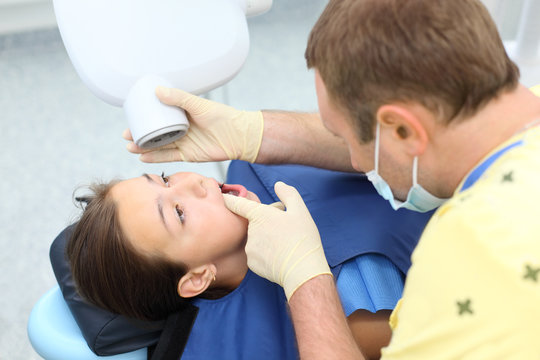 Dentist prepares to make tooth x-ray image for girl