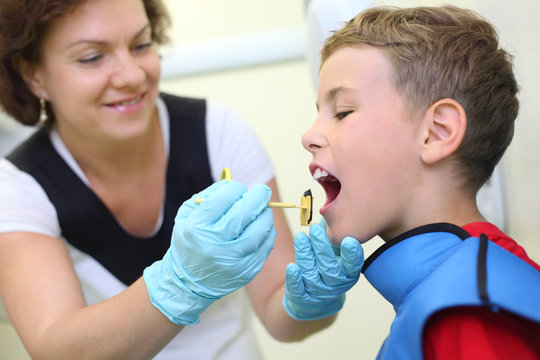 Dentist prepares boy for tooth x-ray image in dental clinic.