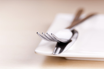 Knife and fork cutlery with a white plate in very shallow focus