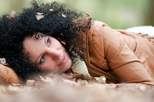 junge Frau liegt im Herbstlaub