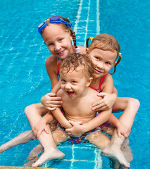 two little girls and little boy playing in the pool