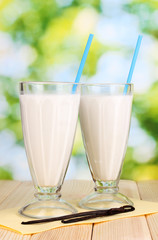 Vanilla milk shakes on wooden table on bright background