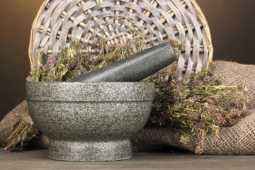 Thyme herb and mortar on wooden table on brown background