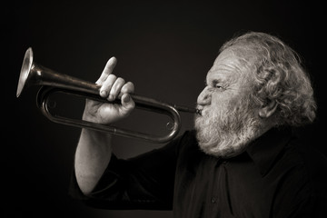 Bearded old man blowing a bugle with gusto
