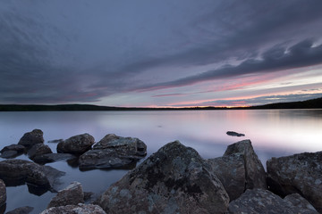 A calm lake, rocks in the foreground