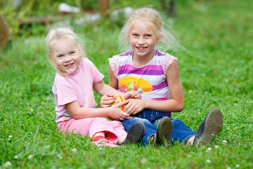 Naklejka na ściany i meble Two little girls playing in the meadow