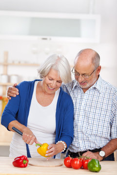 älteres ehepaar schneidet gemüse in der küche