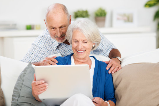 lachendes älteres ehepaar schaut auf laptop