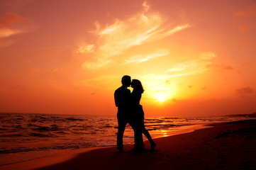 an amorous couple are kissing at sundown - Powered by Adobe