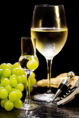 grappa glass with blurred wine glass on black background