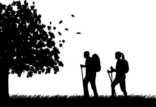 Hiking couple with rucksacks in autumn or fall silhouette