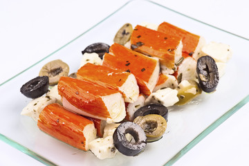 salad of surimi, olives and cheese; in glass tray