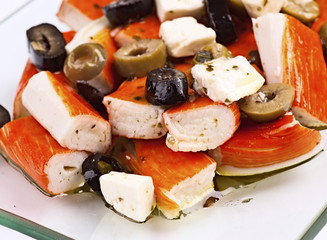 salad of surimi, olives and cheese; in glass tray