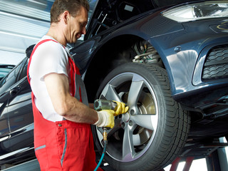 Motor mechanic changes a tyre with new alu rim on a service lift