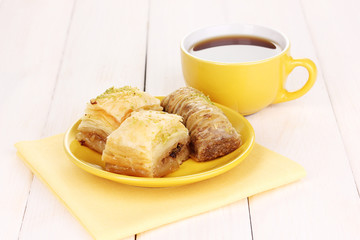 Sweet baklava on plate with tea on wooden background