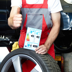 Car mechanic shows thumb up for tire label