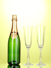 Bottle of champagne and goblets on green background