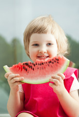 Happy smiling little girl eating watermelon