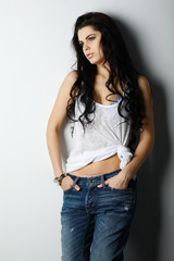Portrait of beautiful girl in jeans standing near a wall