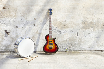electric guitar and drum in front of a vintage wall