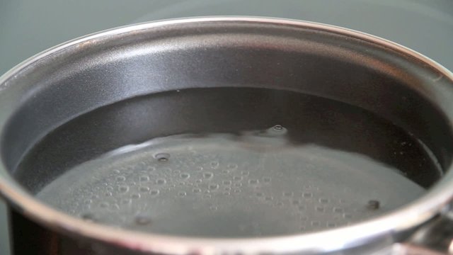 Steam of boiling water on stove in kitchen