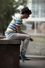Fototapeta premium Handsome man sitting on the curb in city