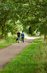 Obraz premium young couple walking their dog along a country path