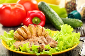 Meat and potatoes on a green salad.