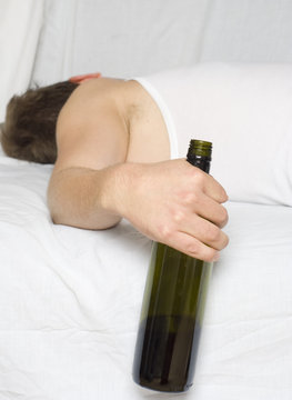 Man in bed with a wine bottle