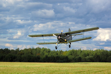 Historic airborne biplane landing at airfield.