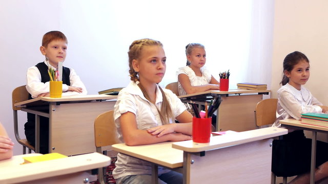 Children sitting at the table and looking at the teacher