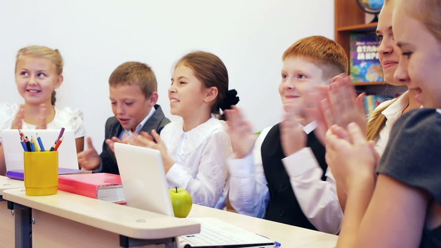 Schoolchildren clapping in the classroom together