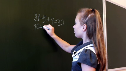 Adorable schoolgirl writing mathematic expression - Powered by Adobe