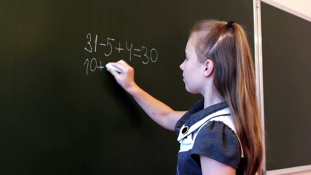 Adorable schoolgirl writing mathematic expression