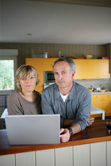 Couple using laptop in kitchen