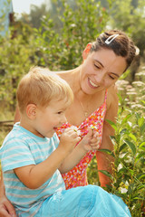 woman with a young son admires daisies