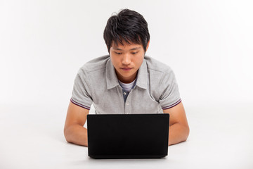 A smiling male working on a laptop isolated on white background