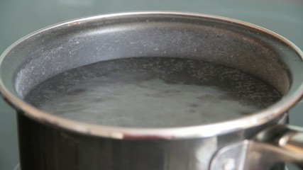 Steam of boiling water on stove in kitchen