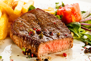 Grilled steaks, French fries and vegetables
